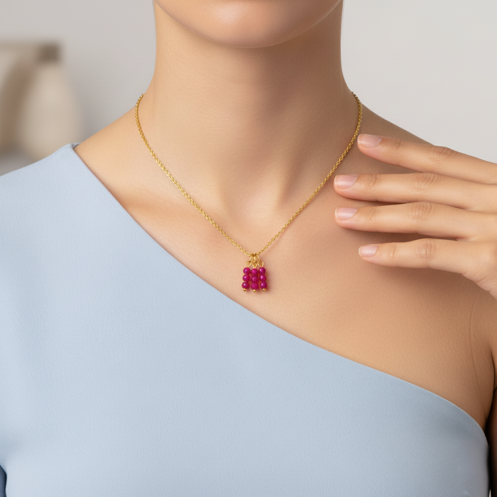 Modelo luciendo un collar dorado con charm de racimo de cuentas fucsias