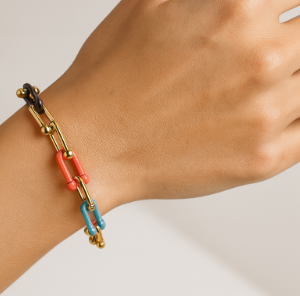 Pulsera multicolor de eslabones bañados en oro en la muñeca de una mujer